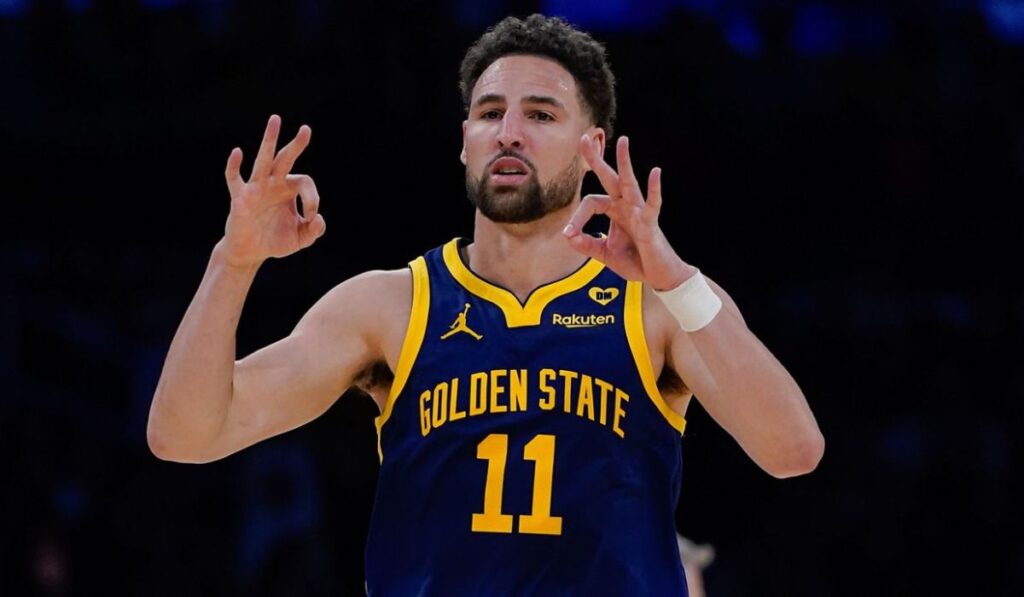 Klay Thompson dribbling a basketball on the court during his preseason debut, looking focused and determined as he prepares to shoot