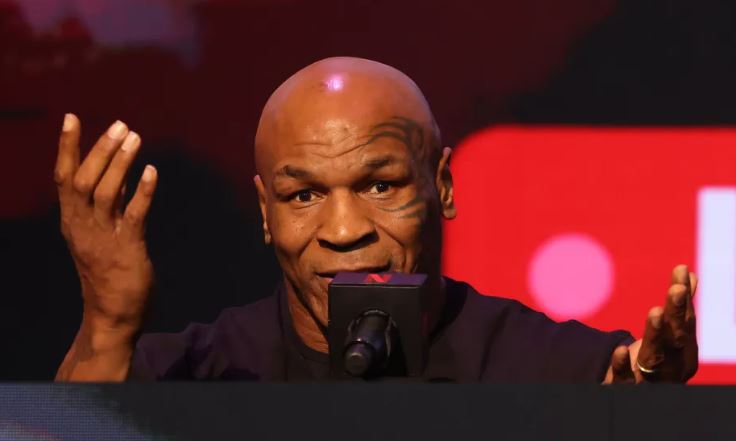 Mike Tyson speaking during an interview, revealing details about his life-threatening medical emergency, with a concerned expression on his face.